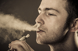 Un homme exhalant la fumée d'une cigarette électronique